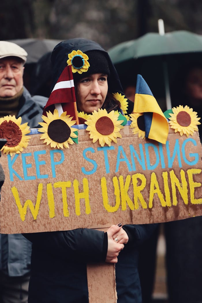 A peaceful protest in Riga, Latvia with signs supporting Ukraine, featuring sunflowers and flags.