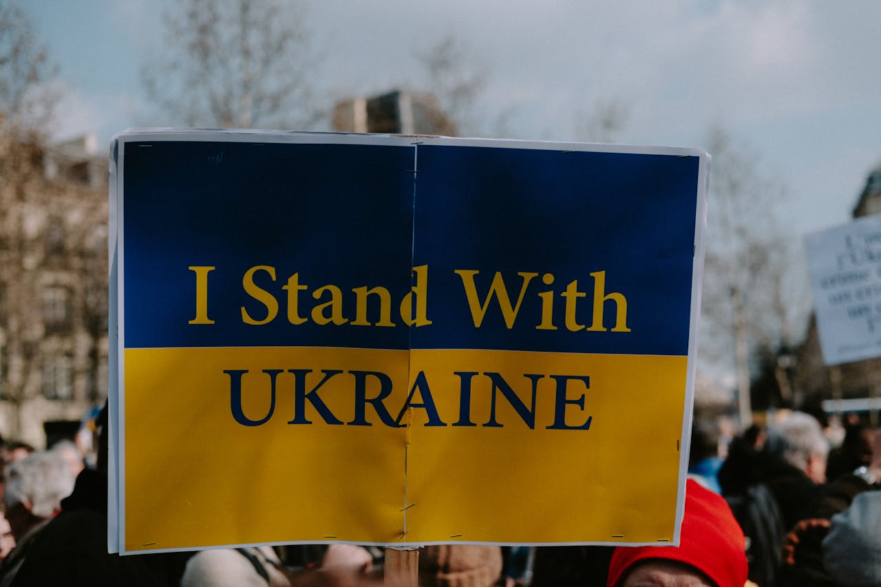 A protest image with a sign reading I Stand With Ukraine, showing solidarity and support.